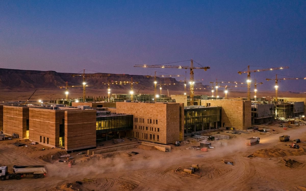 Desert campus construction under floodlight at dusk outside Riyadh